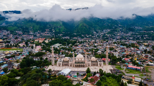 Aerial view of the grand Jalalabad Mosque with its white domes and minarets nestled among the urban sprawl and misty green mountains of Muzaffarabad Azad Kashmir Pakistan. Aerial view of the grand Jalalabad Mosque with its white domes and minarets nestled among the urban sprawl and misty green mountains of Muzaffarabad Azad Kashmir Pakistan.
