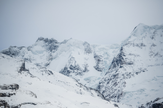 View of crisp white snow blankets the rugged towering mountain range under a soft overcast sky creating a serene yet imposing landscape Murren Switzerland. View of crisp white snow blankets the rugged towering mountain range under a soft overcast sky creating a serene yet imposing landscape Murren Switzerland.