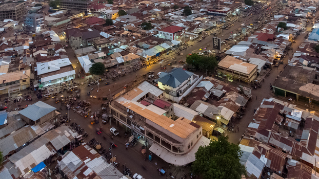 Aerial view of the urban landscape of Tamale featuring dense rooftops busy streets and buildings illuminated at dusk in Tamale Northern Region Ghana. Aerial view of the urban landscape of Tamale featuring dense rooftops busy streets and buildings illuminated at dusk in Tamale Northern Region Ghana.