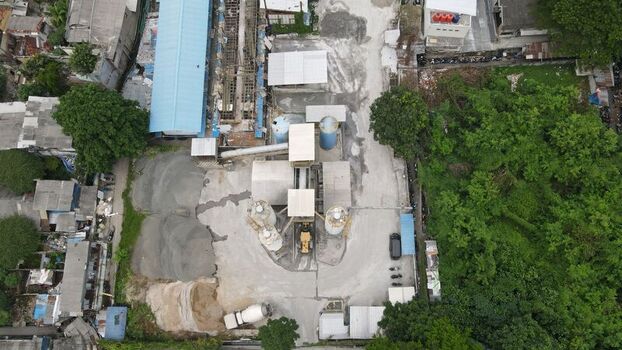 Aerial view of a concrete batching plant with industrial silos machinery and storage areas surrounded by lush green trees in Kecamatan Menteng Daerah Khusus Ibukota Indonesia. Aerial view of a concrete batching plant with industrial silos machinery and storage areas surrounded by lush green trees in Kecamatan Menteng Daerah Khusus Ibukota Indonesia.