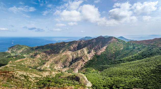 Aerial view of the landscape surrounding Castello del Volterraio with green hills rocky ridges and the blue sea in the background in Portoferraio Toscana Italy.