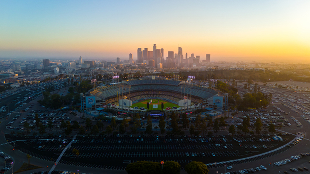 Aerial view of Dodger Stadium basks in the warm glow of a setting sun casting long shadows across the vast parking lots Los Angeles California United States. Aerial view of Dodger Stadium basks in the warm glow of a setting sun casting long shadows across the vast parking lots Los Angeles California United States.