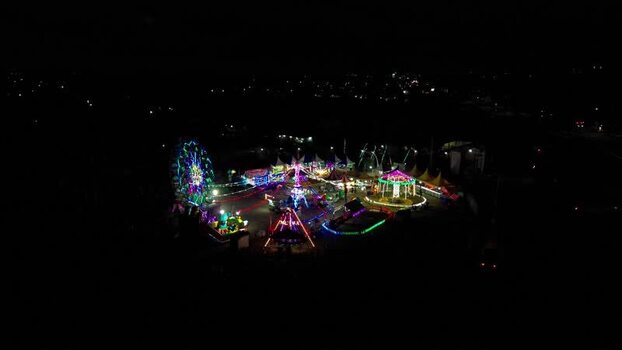 Aerial view of a night carnival with colorful rides in Indonesia.