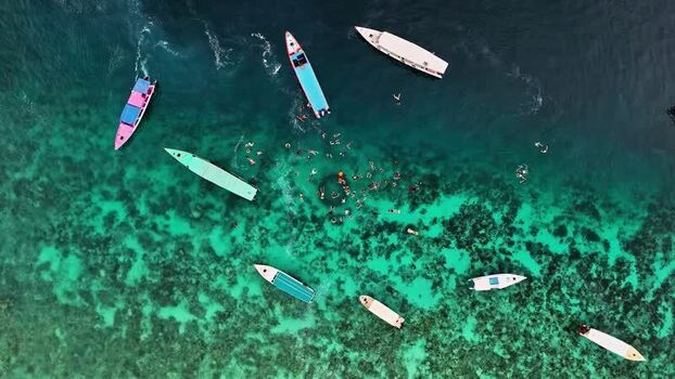 Aerial view of boats and swimmers in clear water Indonesia.