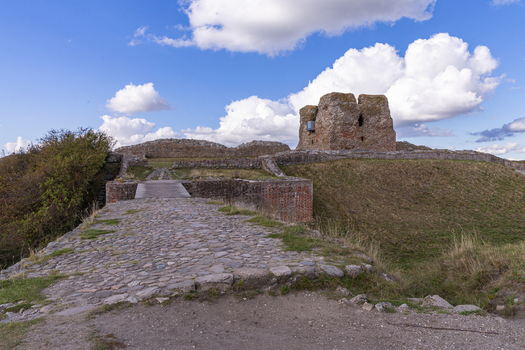 View of the historic ruins of Kalo Castle with its stone walls and cobblestone path set against a blue sky with clouds in Ronde Jutland Denmark. View of the historic ruins of Kalo Castle with its stone walls and cobblestone path set against a blue sky with clouds in Ronde Jutland Denmark.