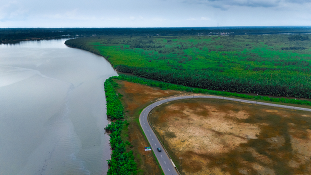 Aerial view of a winding road running alongside a river and lush green vegetation Rivers Nigeria.