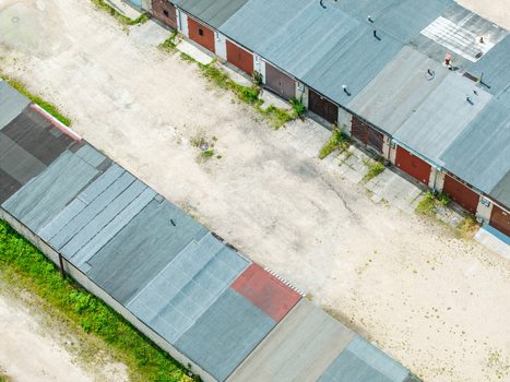 Aerial view of a row of garage units in the Zemgale Suburb with weathered roofs and gravel ground in Riga Latvia.