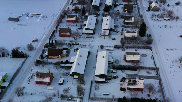 Aerial view of a quiet residential neighborhood with houses featuring snow covered roofs and surrounding winter landscape in Latvia. Aerial view of a quiet residential neighborhood with houses featuring snow covered roofs and surrounding winter landscape in Latvia.