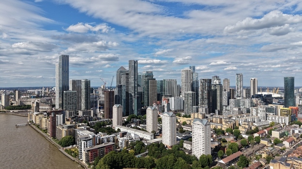 London United Kingdom 16 June 2026 Aerial view of the modern skyscrapers of Canary Wharf financial district with residential blocks and the River Thames under a cloudy sky.