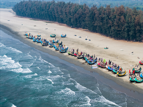 Cox s Bazar Bangladesh 10 March 2026 Aerial view of colorful moon boats lined up on the sandy shore of Cox s Bazar beach with waves and a lush forest background. Cox s Bazar Bangladesh 10 March 2026 Aerial view of colorful moon boats lined up on the sandy shore of Cox s Bazar beach with waves and a lush forest background.