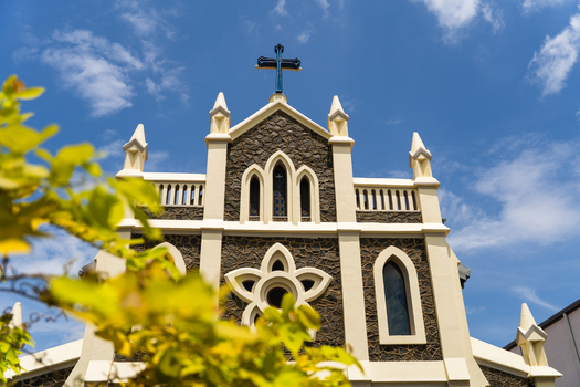 View of the historic St. Mary s Church featuring stone walls and a blue cross under a bright sky with yellow leaves in the foreground in Matara Southern Province Sri Lanka.