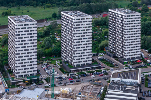 Aerial view of three modern high rise apartment buildings with distinctive black and white facades surrounded by green spaces and urban infrastructure Warsaw Masovian Voivodeship Poland.