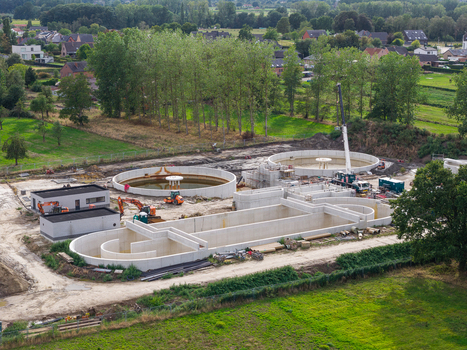 Vilvoorde Belgium 30 August 2026 Aerial view of a wastewater treatment plant under construction featuring large circular concrete tanks machinery and a crane in a rural setting. Vilvoorde Belgium 30 August 2026 Aerial view of a wastewater treatment plant under construction featuring large circular concrete tanks machinery and a crane in a rural setting.