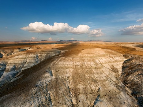 Aerial view of the arid rugged landscape with rolling hills layered sedimentary rock formations and a vast horizon under a blue sky in Sivrihisar Eskisehir Turkey. Aerial view of the arid rugged landscape with rolling hills layered sedimentary rock formations and a vast horizon under a blue sky in Sivrihisar Eskisehir Turkey.