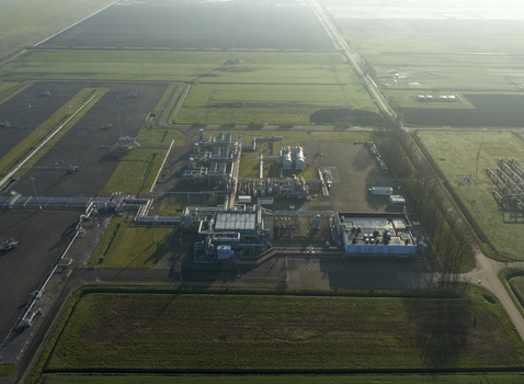 Aerial view of the natural gas mining facility with industrial infrastructure pipelines and storage tanks surrounded by green agricultural fields in Slochteren Groningen Netherlands. Aerial view of the natural gas mining facility with industrial infrastructure pipelines and storage tanks surrounded by green agricultural fields in Slochteren Groningen Netherlands.