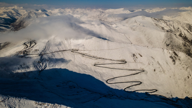 Aerial view of Babusar Pass winding through snow covered mountain peaks under a layer of clouds Babusar KPK Pakistan. Aerial view of Babusar Pass winding through snow covered mountain peaks under a layer of clouds Babusar KPK Pakistan.