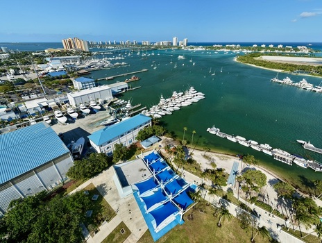 Aerial view of Riviera Beach Marina Village with numerous yachts docked in turquoise water under a clear blue sky in Riviera Beach Florida United States. Aerial view of Riviera Beach Marina Village with numerous yachts docked in turquoise water under a clear blue sky in Riviera Beach Florida United States.
