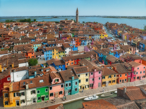 Aerial view of a vibrant tapestry of brightly colored houses with terracotta roofs sprawling towards a distant campanile Burano Venice Veneto Italy. Aerial view of a vibrant tapestry of brightly colored houses with terracotta roofs sprawling towards a distant campanile Burano Venice Veneto Italy.