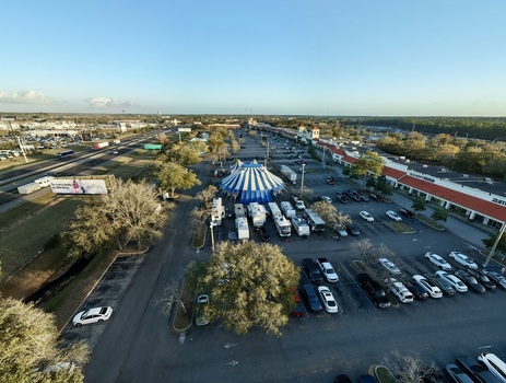 Aerial view of a vibrant circus tent standing out amid the surrounding parked vehicles and buildings showcasing a blend of entertainment and commerce St. Augustine Florida United States. Aerial view of a vibrant circus tent standing out amid the surrounding parked vehicles and buildings showcasing a blend of entertainment and commerce St. Augustine Florida United States.
