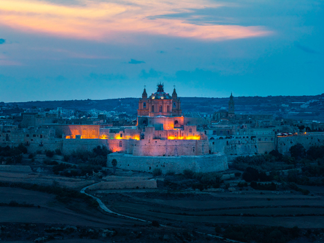 Aerial view of the historic fortified city of Mdina at dusk featuring the illuminated St. Paul s Cathedral and ancient stone walls in Mdina Western Region Malta. Aerial view of the historic fortified city of Mdina at dusk featuring the illuminated St. Paul s Cathedral and ancient stone walls in Mdina Western Region Malta.