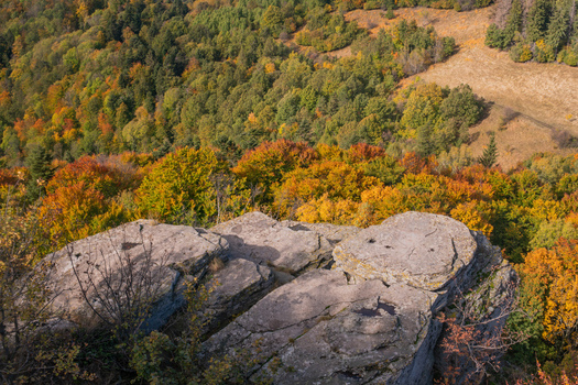 Aerial view of Sitno in Stiavnicke Vrchy featuring rugged rock formations overlooking a dense forest with vibrant autumn foliage in Ilija Banska Bystrica Regio Slovakia.