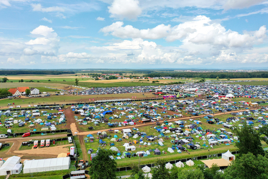 Herzogenaurach Germany 27 July 2025 Aerial view of the Open Beatz Festival campsite featuring rows of colorful tents a large parking area and expansive green fields under a bright cloudy sky. Herzogenaurach Germany 27 July 2025 Aerial view of the Open Beatz Festival campsite featuring rows of colorful tents a large parking area and expansive green fields under a bright cloudy sky.