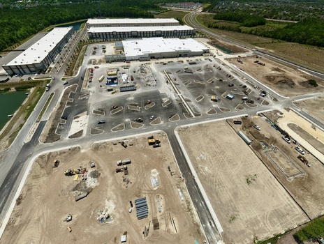 Aerial view of the construction site at Foundry Lane featuring large white warehouses heavy machinery and newly paved roads in World Golf Village Florida United States.