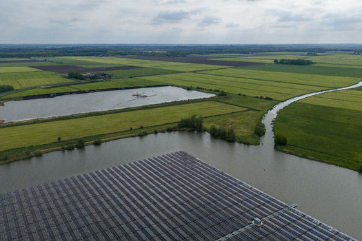 Aerial view of floating solar panels on a lake surrounded by lush green agricultural fields and a winding canal under a cloudy sky Beilen Drenthe Netherlands. Aerial view of floating solar panels on a lake surrounded by lush green agricultural fields and a winding canal under a cloudy sky Beilen Drenthe Netherlands.