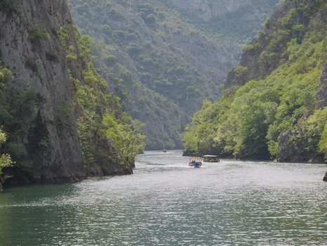 View of Matka Canyon with boats navigating the river surrounded by steep rocky cliffs and lush green vegetation in Matka Grad Skopje North Macedonia.
