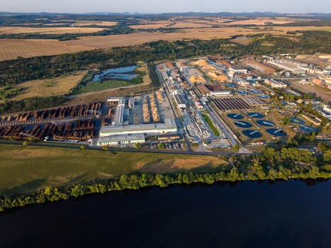 Aerial view of the Security Paper Mill facility featuring industrial buildings wood storage piles and water treatment basins along the Elbe River in Steti Ustecky kraj Czechia. Aerial view of the Security Paper Mill facility featuring industrial buildings wood storage piles and water treatment basins along the Elbe River in Steti Ustecky kraj Czechia.