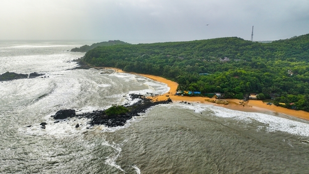 Aerial view of Om Beach with its distinctive rocky coastline sandy shores and lush green hills under an overcast sky in Gokarna Karnataka India. Aerial view of Om Beach with its distinctive rocky coastline sandy shores and lush green hills under an overcast sky in Gokarna Karnataka India.