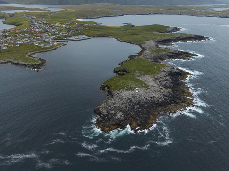 Aerial view of Fugla Ness Lighthouse situated on a rocky headland with the village of Hamnavoe and the surrounding coastline in the background Hamnavoe Scotland United Kingdom.