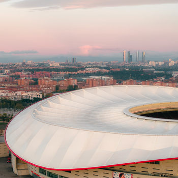 Aerial view of Riyadh Air Metropolitano Stadium with its distinctive white roof and the Madrid city skyline in the background during sunset in Madrid Comunidad de Madrid Spain.