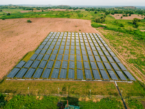 Aerial view of a large solar farm with rows of photovoltaic panels installed on a grassy field in a rural landscape in Ogun State Nigeria.