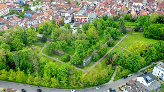 Aerial view of Stadtpark with its lush green trees walking paths and historic stone walls overlooking the town rooftops in Forchheim Bayern Germany. Aerial view of Stadtpark with its lush green trees walking paths and historic stone walls overlooking the town rooftops in Forchheim Bayern Germany.