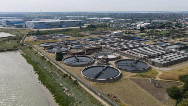 Aerial view of a large water treatment plant with circular sedimentation tanks and rectangular treatment beds situated along the riverbank in Dartford England United Kingdom.