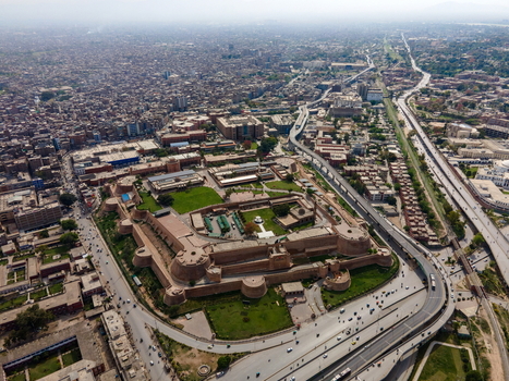 Aerial view of Bala Hisar Fort surrounded by historic walls green courtyards and the dense urban sprawl of Peshawar Khyber Pakhtunkhwa Pakistan.