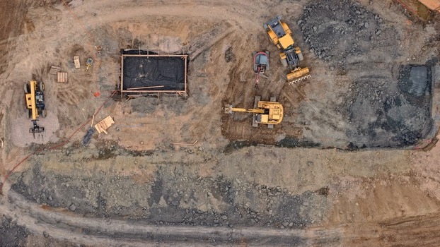 Aerial view of a construction site featuring heavy machinery including excavators and loaders working on a dirt foundation in Denver Colorado United States. Aerial view of a construction site featuring heavy machinery including excavators and loaders working on a dirt foundation in Denver Colorado United States.