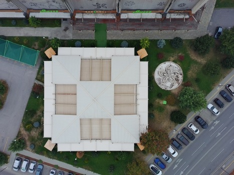 Aerial view of Universiada Hall and Coffee Shop with its square roof structure surrounding green space and nearby parking area in Sofia Sofia City Province Bulgaria.
