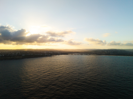 Aerial view of the coastline at sunset with golden light reflecting on the ocean and the town of Dee Why New South Wales Australia. Aerial view of the coastline at sunset with golden light reflecting on the ocean and the town of Dee Why New South Wales Australia.
