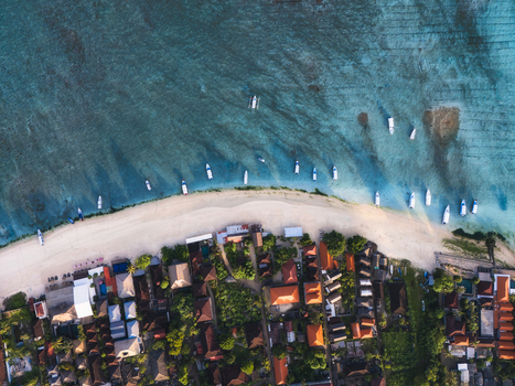 Aerial view of boats resting on the shore where the turquoise sea meets the sandy beach Lembongan Bali Indonesia.