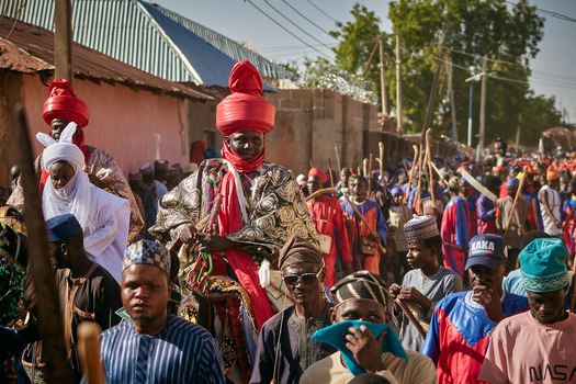 Zaria Nigerian 21 March 2026 View of a bustling cultural procession with elegantly robed figures in vibrant red turbans their rich colors contrasting with earthy street tones. Zaria Nigerian 21 March 2026 View of a bustling cultural procession with elegantly robed figures in vibrant red turbans their rich colors contrasting with earthy street tones.