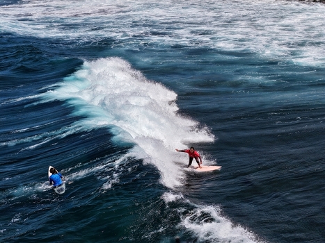 Aerial view of surfers riding large waves with white foam at Praia do Areal de Santa Barbara in Ribeira Grande Acores Portugal. Aerial view of surfers riding large waves with white foam at Praia do Areal de Santa Barbara in Ribeira Grande Acores Portugal.