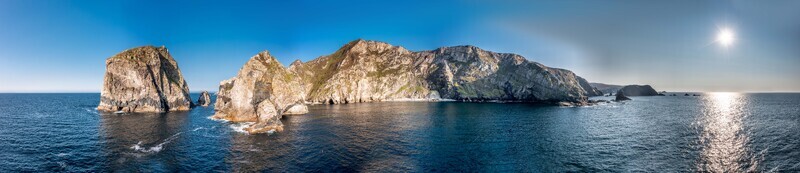 Aerial view of the dramatic cliffs and rugged coastline of Glenlough Bay with the Atlantic Ocean sparkling under the sun in Ardara County Donegal Ireland.