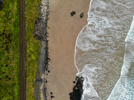 Aerial view of the railway tracks running along the sandy beach and crashing waves at Downhill Beach near Mussenden Temple in Coleraine Northern Ireland United Kingdom. Aerial view of the railway tracks running along the sandy beach and crashing waves at Downhill Beach near Mussenden Temple in Coleraine Northern Ireland United Kingdom.