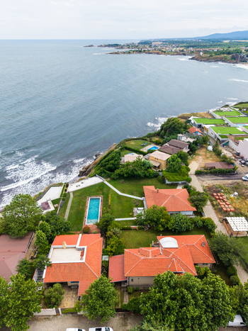 Aerial view of coastal villas with red tiled roofs and swimming pools situated on a cliff overlooking the Black Sea in Lozenets Burgas Bulgaria.