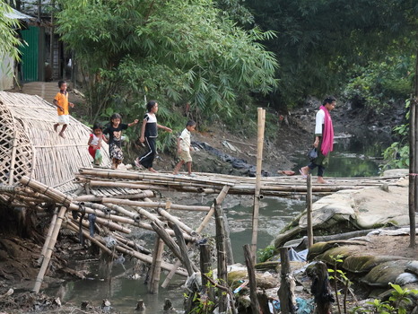 Cox s Bazar Bangladesh 19 July 2026 View of children and a woman crossing a makeshift bamboo bridge over a stream in the Rohingya refugee camp.