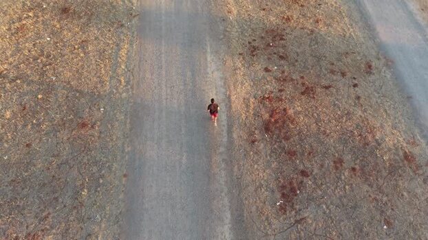 Aerial view of a man running on a dirt path in Caceres Spain.