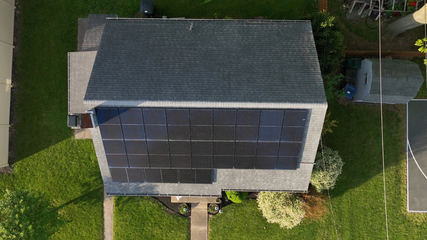 Aerial view of a residential house roof covered with solar panels surrounded by a green lawn and backyard in Denver Pennsylvania United States. Aerial view of a residential house roof covered with solar panels surrounded by a green lawn and backyard in Denver Pennsylvania United States.