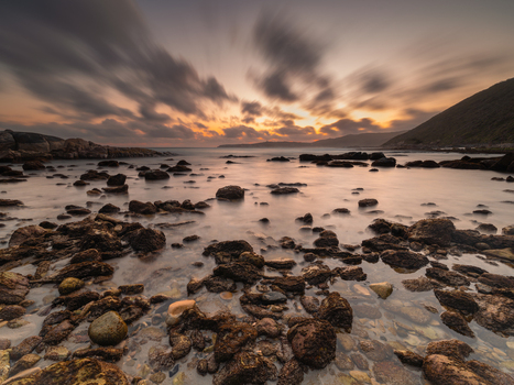 View of Blowholes Road coastline with scattered rocks in the foreground calm water and a dramatic sunset sky with long exposure clouds Torndirrup Western Australia Australia. View of Blowholes Road coastline with scattered rocks in the foreground calm water and a dramatic sunset sky with long exposure clouds Torndirrup Western Australia Australia.